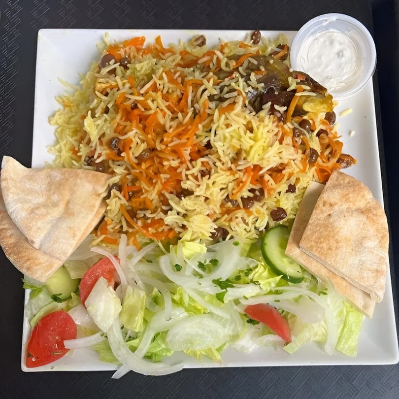 Middle Eastern rice pilaf with carrots, raisins, salad, pita bread, and a side of white sauce.