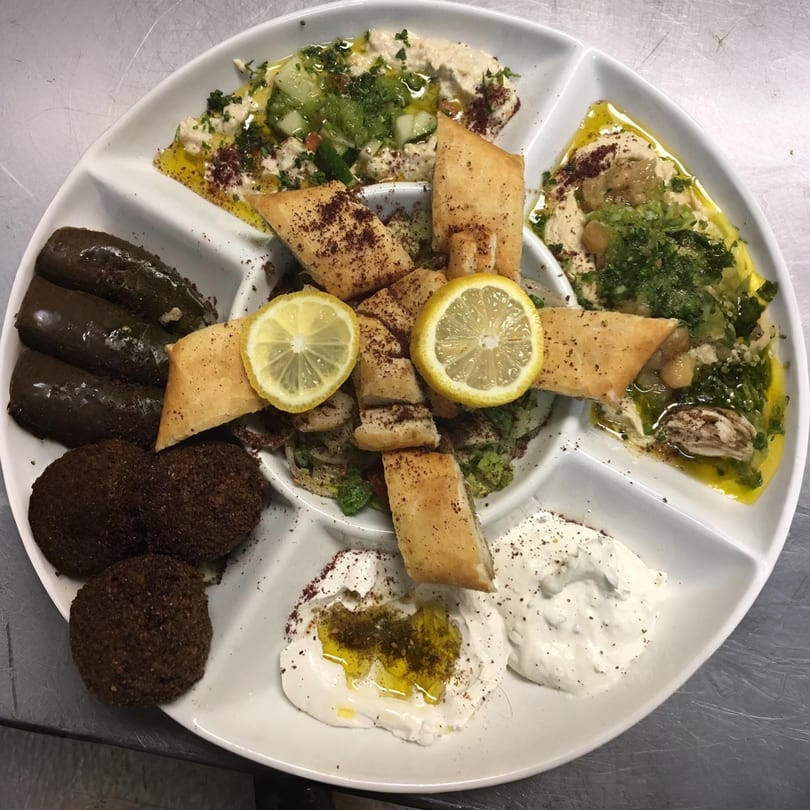 A Bethlehem Restaurant & Grocery platter with hummus, falafel, stuffed grape leaves, and pita bread.